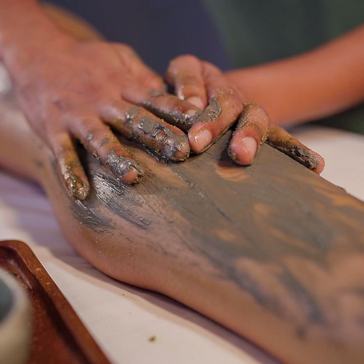 Therapist applying an exfoliating clay treatment to the foot during a body scrub at Blossoms Massage Spa, Kilimani