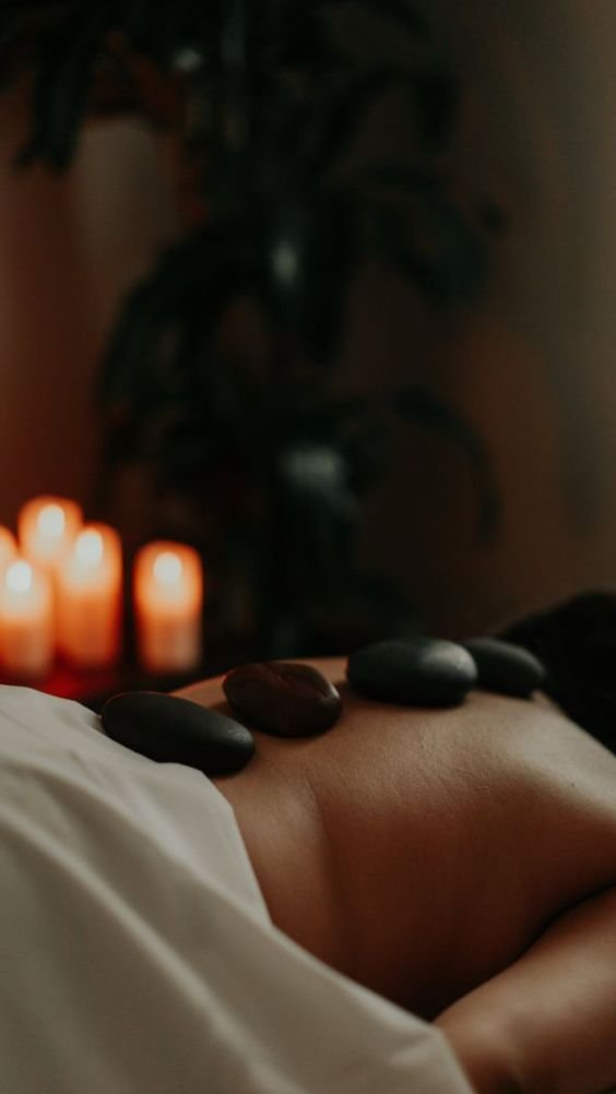 Hot stones resting along the back beside candlelight during a hot stone massage at Blossoms Massage Spa, Kilimani
