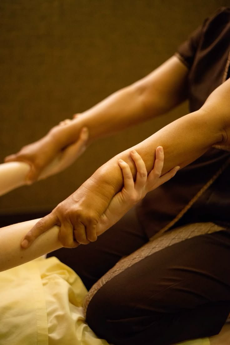 Therapist stretching a client's arm during a traditional Thai massage at Blossoms Massage Spa, Kilimani